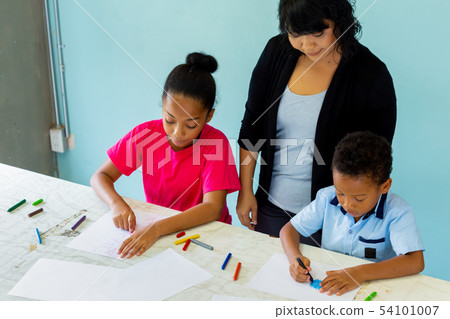 Young teacher giving African American kids an art lesson and teaching how to draw Young teacher giving African American kids an art lesson and teaching how to draw 54101007