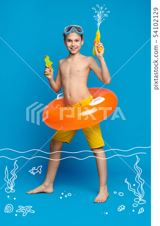 Teenage boy swimming in water with water guns and inflatable ring Teenage boy swimming in water with water guns and inflatable ring 54102129