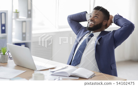 Young african businessman in formalwear relaxing at workplace Young african businessman in formalwear relaxing at workplace 54102475