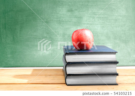 Pile of books with apple on the wooden table 54103215