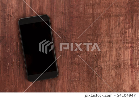 A smartphone, shot from the top on a dark wooden background, a mockup of a blank screen with copy 54104947