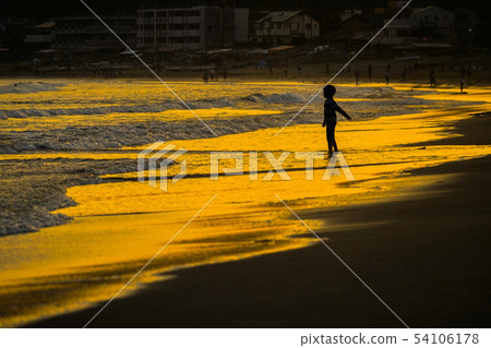 Child playing on the beach at dusk Child playing on the beach at dusk 54106178