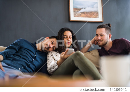 A group of young friends with smartphone sitting on sofa indoors, house sharing concept. 54106941