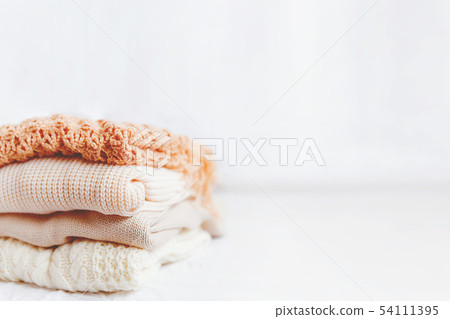 Pile of beige woolen clothes on a white background 54111395