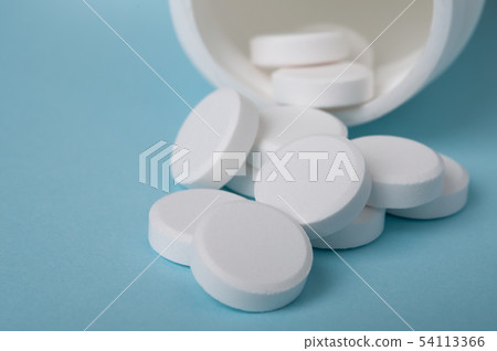 closed up white pills spilling oyt of the bottle 54113366