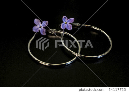 Shiny round thin metal earrings and lilac flowers. 54117733