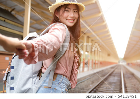 man & woman with backpack holding hands waiting for train at railway station. loving couple traveler travel together man & woman with backpack holding hands waiting for train at railway station. loving couple traveler travel together 54119451