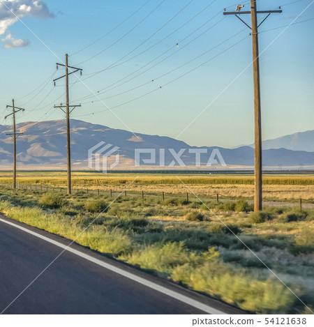 Power lines on grassland against mountain and sky 54121638