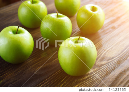 Group of green apples on brown wooden background. 54123565