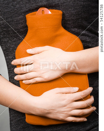 Girl having stomach ache, holding hot water bottle 54125786