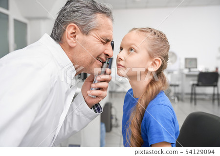 Oculist looking through special tool at eye pupil in clinic 54129094