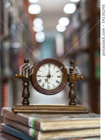 Old Alarm clock on stack of book with blur library 54130248