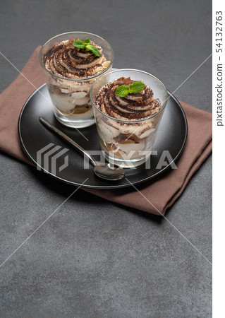 Classic tiramisu dessert in a glass on dark concrete background Classic tiramisu dessert in a glass on dark concrete background 54132763