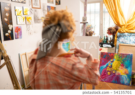 Red-haired artist standing near white canvas and window 54135701