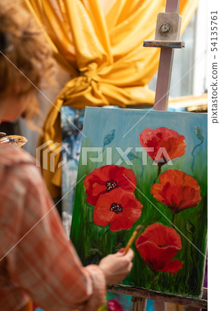 Curly red-haired artist standing near canvas with red poppies 54135761