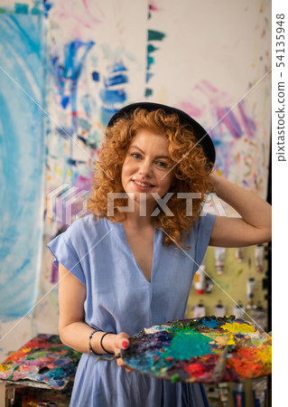 Young appealing artist holding palette with colorful paints 54135948