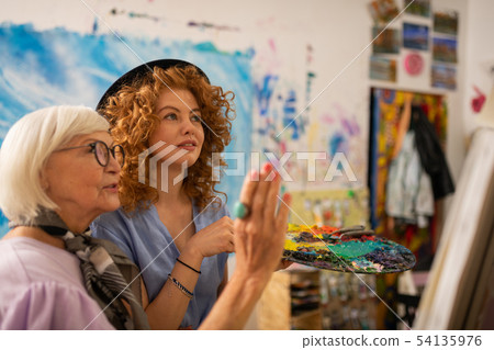 Art teacher in glasses feeling satisfied with work of her student 54135976