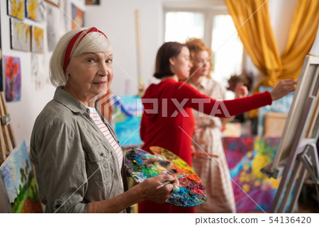 Famous artist standing in workshop near her students Famous artist standing in workshop near her students 54136420