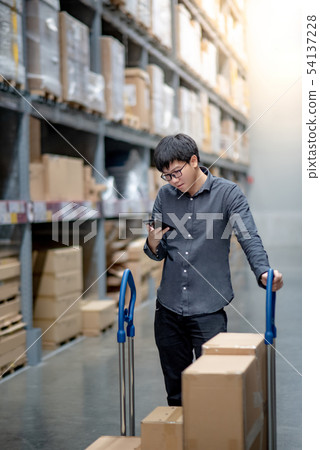 Asian shopper checking shopping list in warehouse Asian shopper checking shopping list in warehouse 54137228