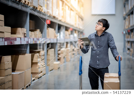 Asian man doing stocktaking on tablet in warehouse Asian man doing stocktaking on tablet in warehouse 54137229