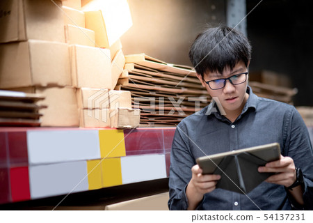 Asian man doing stocktaking on tablet in warehouse 54137231