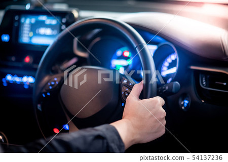Driver hand holding steering wheel in the car 54137236