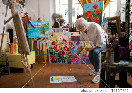 Artist putting paper on floor and sprinkling some paint Artist putting paper on floor and sprinkling some paint 54137262