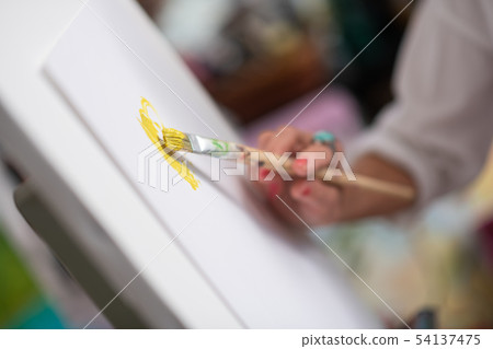 Close up of painting brush with bright yellow gouache Close up of painting brush with bright yellow gouache 54137475