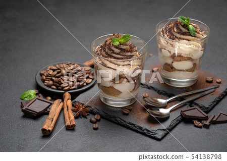Classic tiramisu dessert in a glass on stone serving board on dark concrete background 54138798