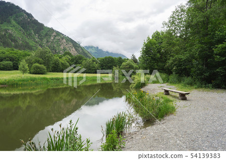Beautiful mountain forest landscape. Bench by the lake overlooking the mountains 54139383