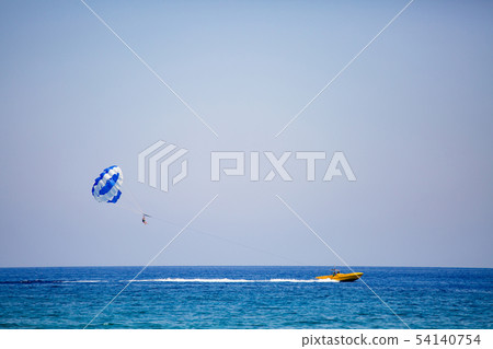 Couple of tourists flies on a blue and white parachute Couple of tourists flies on a blue and white parachute 54140754