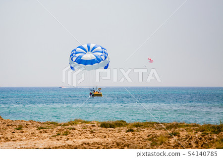 Couple of tourists flies on a blue and white parachute 54140785
