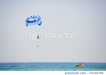 Couple of tourists flies on a blue and white parachute 54140796