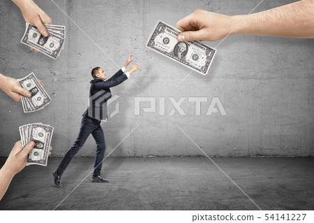 Side view of little businessman reaching out for one of dollar bills given to him by big hands all Side view of little businessman reaching out for one of dollar bills given to him by big hands all 54141227