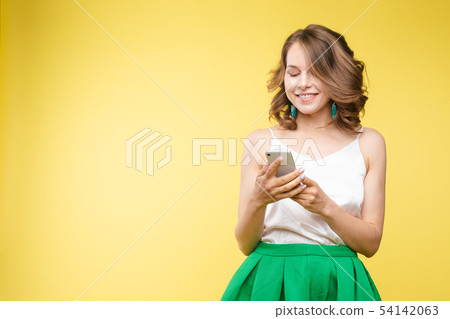 Pretty girl pointing at cell phone.Studio portrait 54142063