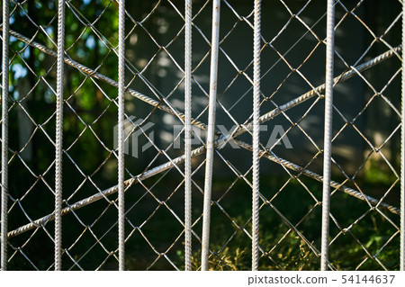 Green backgdefocused behind grey rusty grid 54144637