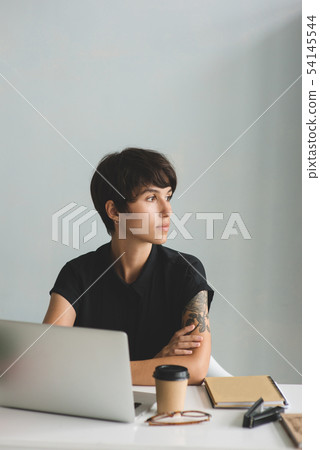Young business woman sitting at the desk with arms crossed and looking away. 54145544