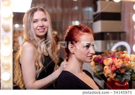 Beautiful, red-haired girl with long hair, hairdresser weaves a French braid, in a beauty salon Beautiful, red-haired girl with long hair, hairdresser weaves a French braid, in a beauty salon 54145973