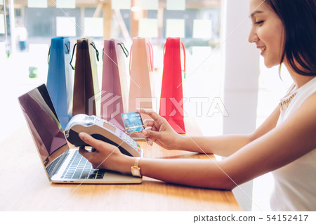woman using credit card swiping machine with shopping bags on table. payment with nfc technology woman using credit card swiping machine with shopping bags on table. payment with nfc technology 54152417