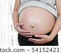 Body part pregnant belly near window at home. 54152421