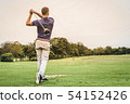 Back of golfer hitting ball on green field with 54152426