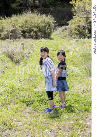 Elementary school student sister taking a walk on a rural road Summer vacation image 54154106