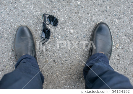 View of the feet of a man and broken sunglasses View of the feet of a man and broken sunglasses 54154192