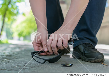 View of the feet of a man and broken sunglasses View of the feet of a man and broken sunglasses 54154673