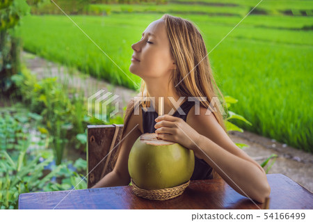 Young woman with fresh coconut cocktail in the background of a rice field 54166499