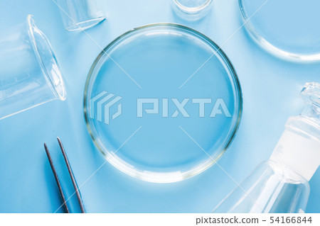 Petri dish with liquids and pincers in laboratory on blue. Fluid testing. 54166844
