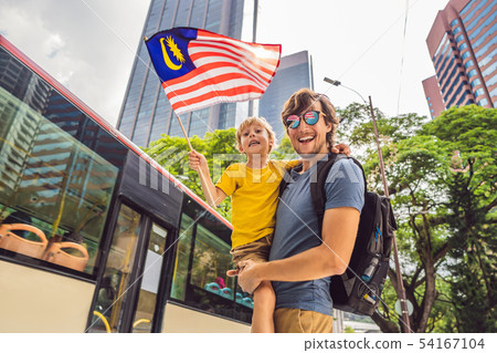 Dad and son tourists in Malaysia with the flag of Malaysia near the skyscrapers. Traveling with kids Dad and son tourists in Malaysia with the flag of Malaysia near the skyscrapers. Traveling with kids 54167104