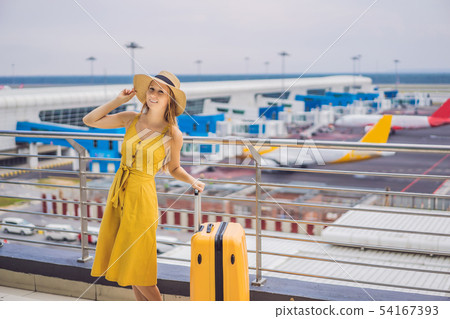 Start of her journey. Beautiful young woman ltraveler in a yellow dress and a yellow suitcase is Start of her journey. Beautiful young woman ltraveler in a yellow dress and a yellow suitcase is 54167393