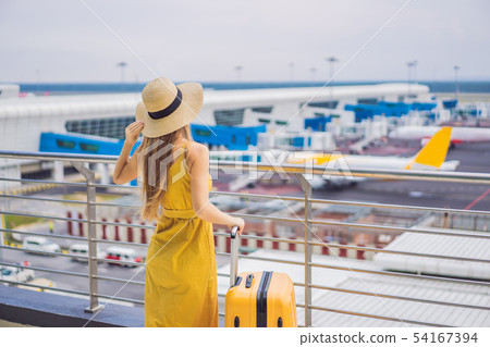 Start of her journey. Beautiful young woman ltraveler in a yellow dress and a yellow suitcase is Start of her journey. Beautiful young woman ltraveler in a yellow dress and a yellow suitcase is 54167394