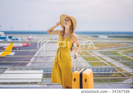 Start of her journey. Beautiful young woman ltraveler in a yellow dress and a yellow suitcase is 54167586